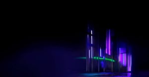 Imagen con fondo oscuro y estructuras verticales iluminadas en tonos morados, azules y verdes, creando un efecto futurista y abstracto. Las luces reflejan sobre una superficie brillante, evocando tecnología y modernidad.