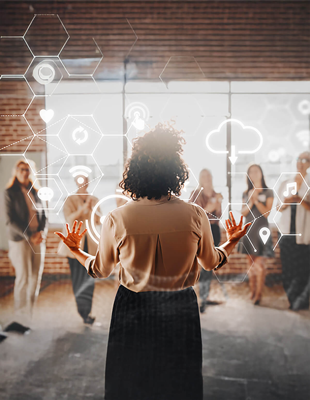 Persona frente a un grupo, interactuando con iconos digitales proyectados en el aire en un entorno tipo oficina.